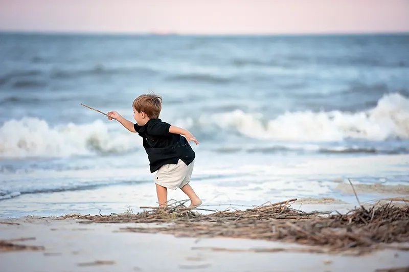 A young boy playing at the water's edge on a beach.