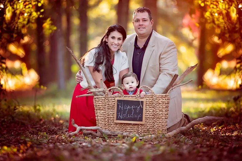 The Lawless family holiday portrait, with their baby in a basket among autumn trees.