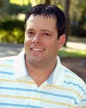 Dr. Daniel P. Lawless, DMD, smiling, in a striped polo shirt outdoors.