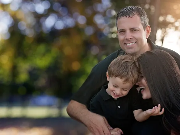 Dr. Lawless with his family in a park, all three smiling.