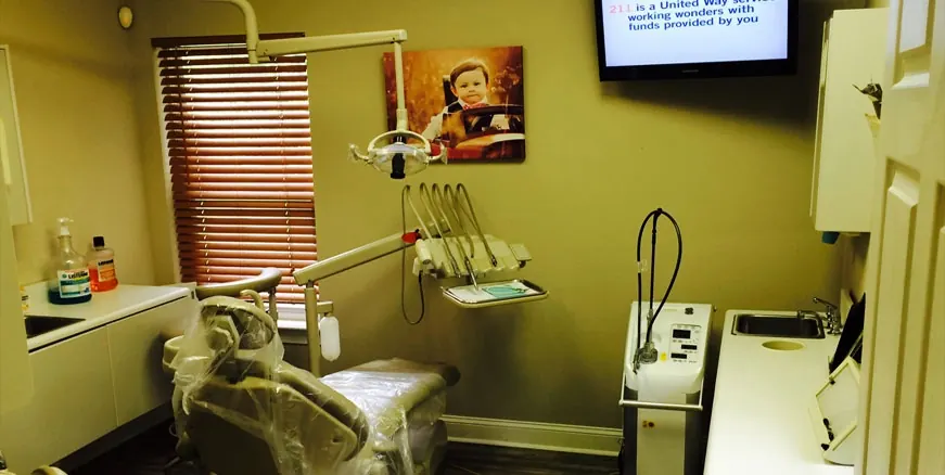 A private treatment room at Hilton Head Dental, with the chair, the overhead light and a television on the wall.