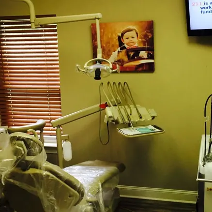 A treatment room at Hilton Head Dental: the dental chair, the light and a child's portrait on the wall.