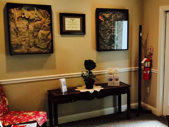Dr. Lawless's framed U.S. Army uniforms, one with the name tape LAWLESS, on the wall of the office.